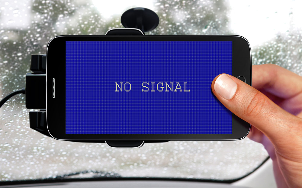 Widok smartfona zawieszonego na szybie samochodu, na którym wyświetlony jest napis "No signal" oznaczający brak sygnału/połączenia GeoNAVI