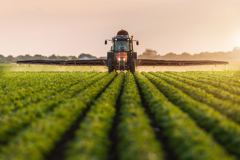 Traktor podczas pracy na polu - spryskiwanie pestycydami pól soi - geonavi.com.pl
